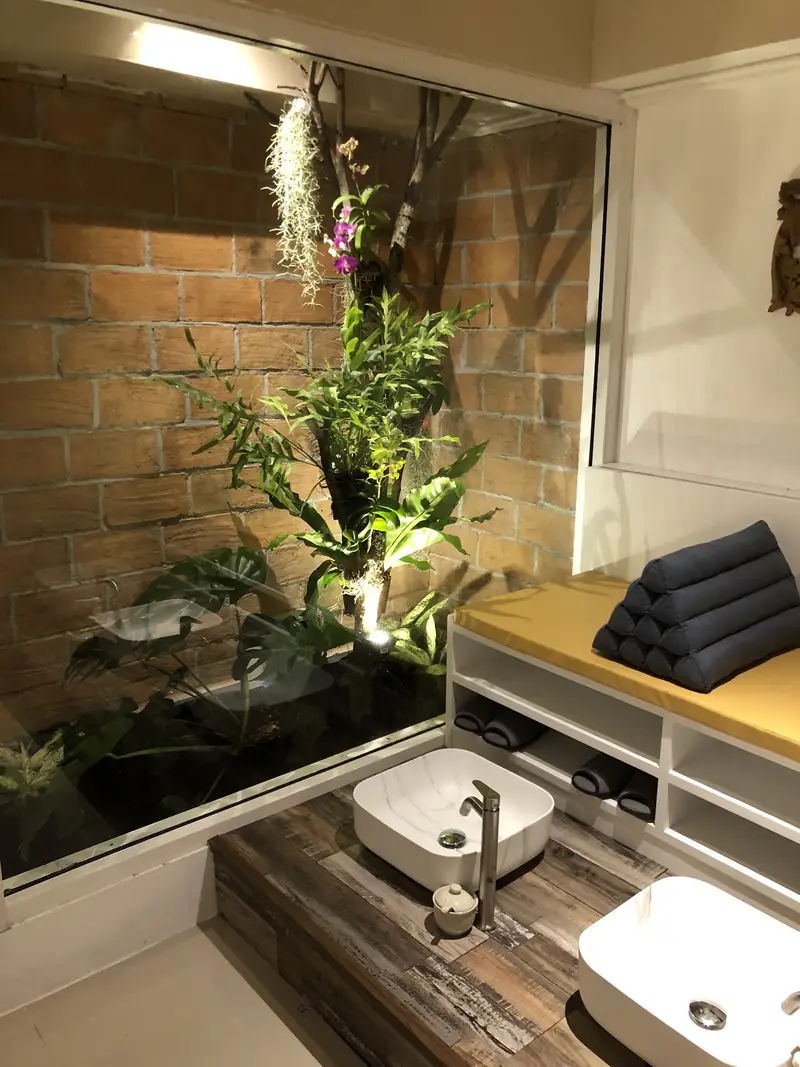 Foot-wash basin beside a glass-walled indoor garden