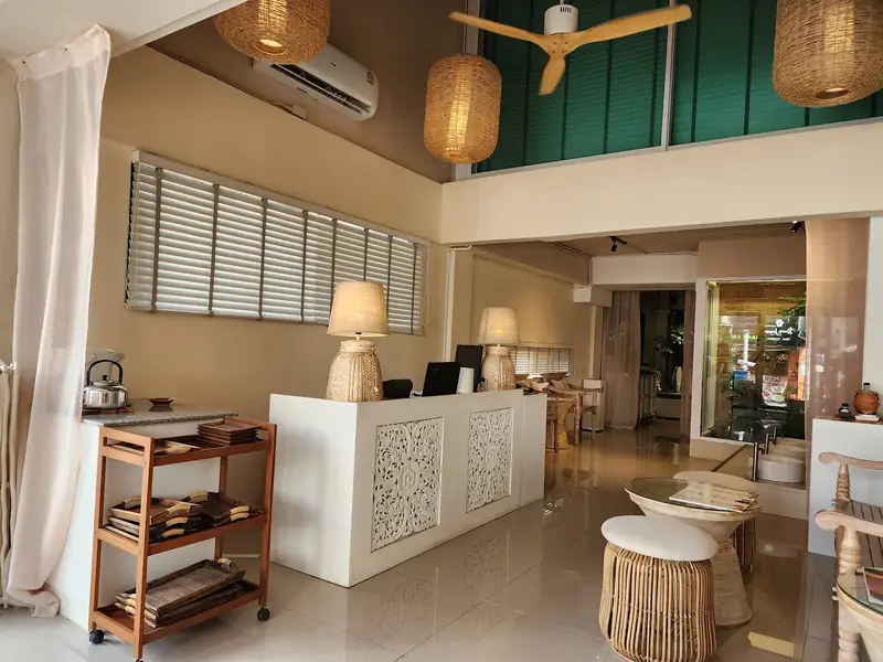 Reception with carved white panels, rattan lamps and a high ceiling with a fan